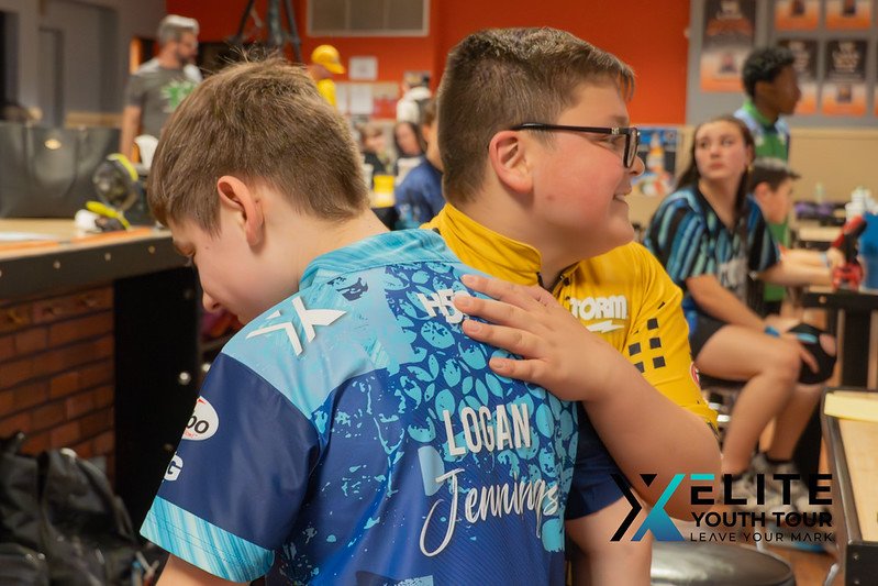 Two youth bowlers sharing a celebratory moment during an Elite Youth Tour bowling event.