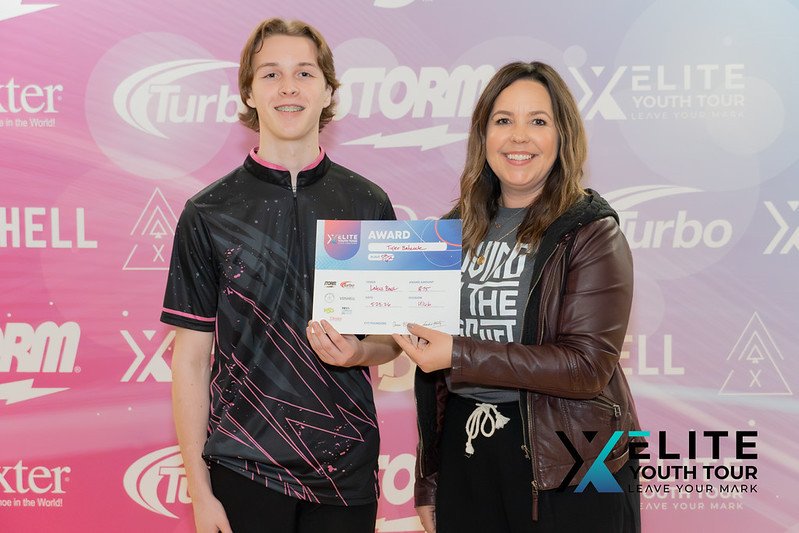Elite Youth Tour bowler receiving an award check from Diandra Asbaty at a youth bowling event.